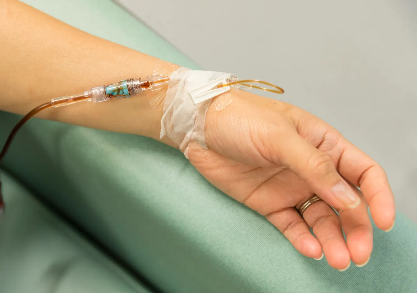Kroplówki witaminowe Koszalin: dłoń z wenflonem i linią infuzyjną na podkładzie